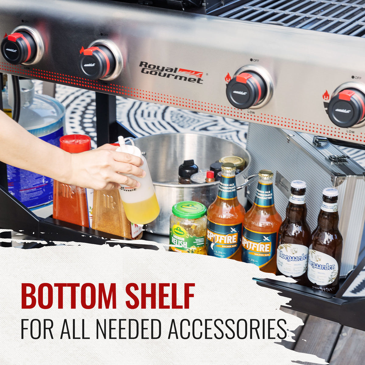 A stainless steel Royal Gourmet  outdoor grill with four black and red control knobs, a hand holding a bottle, and a bottom shelf holding bottles and containers. Text overlay at the bottom reads 'BOTTOM SHELF FOR ALL NEEDED ACCESSORIES'.