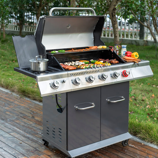 A stainless steel outdoor Royal Gourmet gas grill with a lid, side shelf, and three front control knobs, shown cooking food on a wooden deck with grass and trees in the background.