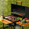 Royal Gourmet Portable grill with food and condiments on a grassy background