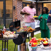 People grilling outdoors with a Royal Gourmet barbecue and various food items on a patio.