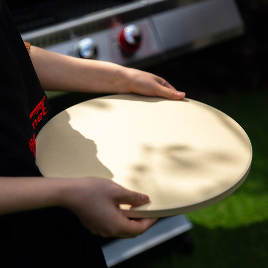 Person holding a pizza stone over a Royal Gourmet grill