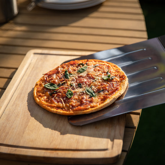 Small pizza on a wooden board with a Royal Gourmet  metal spatula