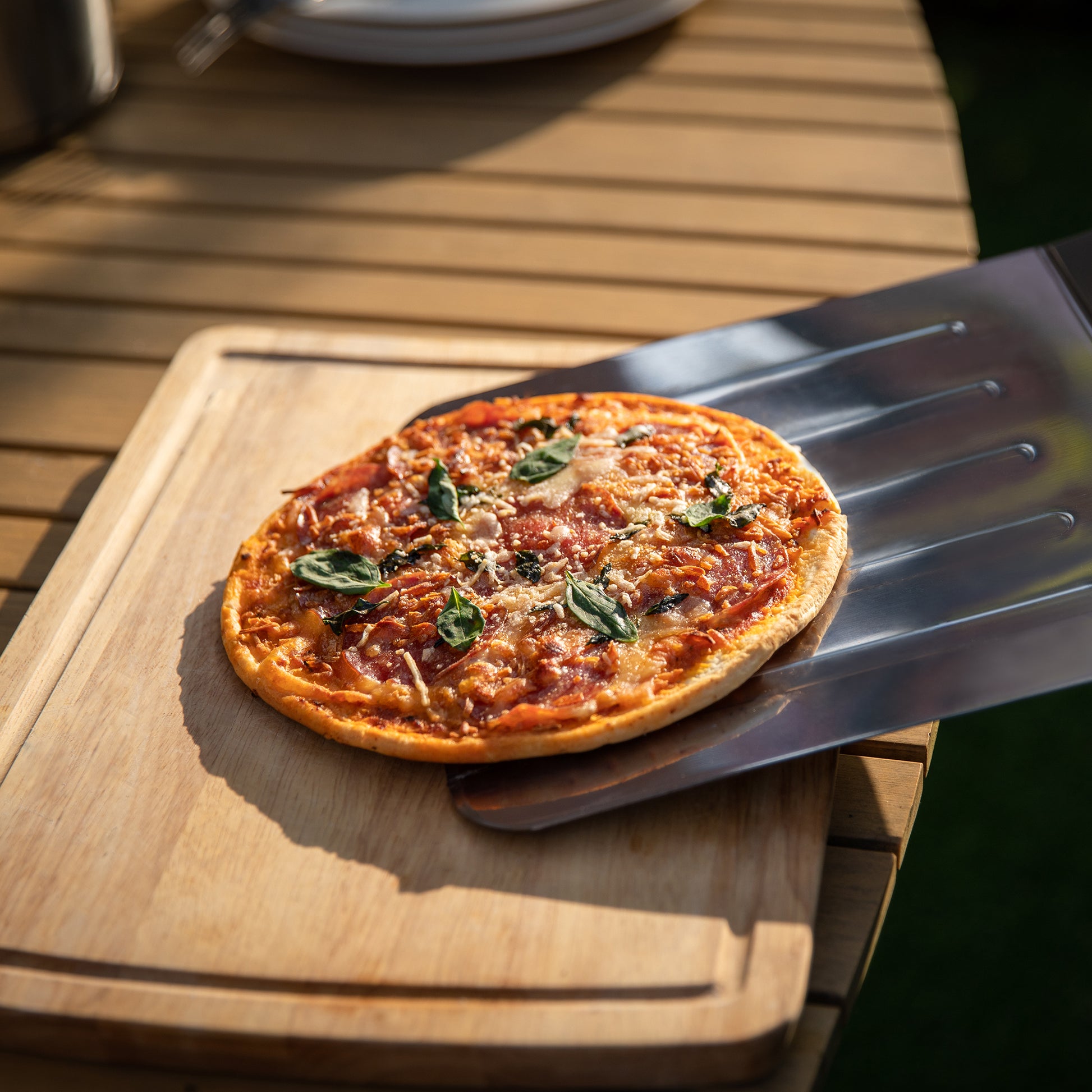 Small pizza on a wooden board with a Royal Gourmet  metal spatula