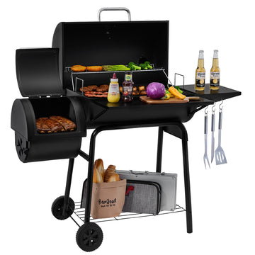 A black Royal Gourmet charcoal grill with a side burner, shown on a white studio background with food, bottles, utensils, and accessories arranged around it. No person or real environment is present, so this is Product/Packaging rather than Lifestyle.